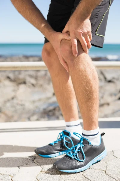 Fit man gripping his injured knee — Stock Photo, Image