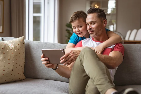 白人父亲和儿子在家里的沙发上使用数字平板电脑 技术和家庭观念 — 图库照片