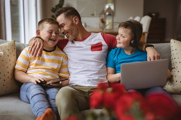 描绘了一个带着笔记本电脑和数码平板电脑的白人父亲和两个儿子在家里微笑的形象 父爱概念 — 图库照片