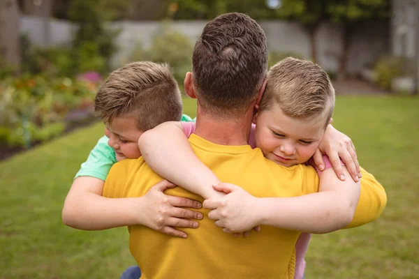 庭に彼の2人の息子を抱いている白人の父親のビューを閉じます 父親と愛の概念 — ストック写真