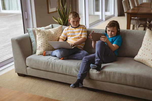 Dois Garotos Caucasianos Usando Laptop Tablet Digital Sentados Sofá Casa — Fotografia de Stock