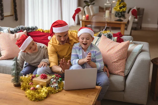 白人の父と2人の息子はクリスマスの間に自宅のラップトップでビデオ通話をしています クリスマスの時期に流行した19種のパンデミックの間の社会的距離は — ストック写真