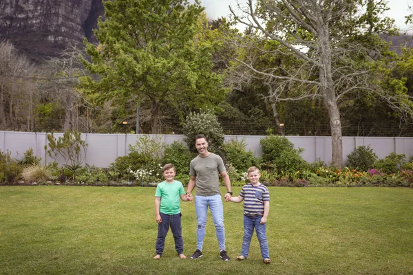 庭に立ちながら笑顔で手をつないでいる白人の父と2人の息子の肖像画 父親と愛の概念 — ストック写真