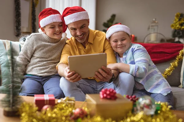 白人の父親と2人の息子がクリスマスの間に自宅のデジタルタブレットでビデオ通話をしています クリスマスの時期に流行した19種のパンデミックの間の社会的距離は — ストック写真