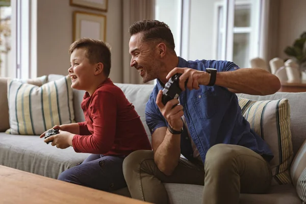 白人父亲和儿子一起玩电子游戏 坐在家里的沙发上 父爱概念 — 图库照片