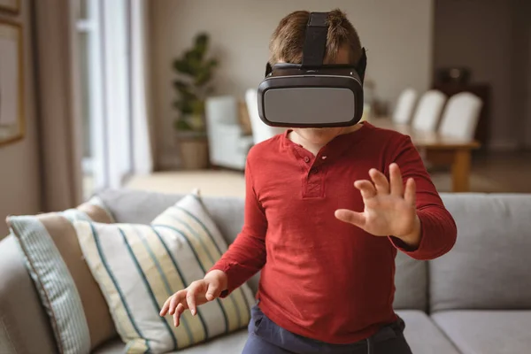 Caucasian boy wearing vr headset gesturing while sitting on the couch at home. gaming and entertainment concept