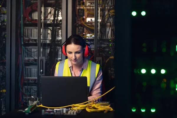 Blanke Vrouwelijke Ingenieur Draagt Oordopjes Met Een Laptop Serverruimte Database — Stockfoto