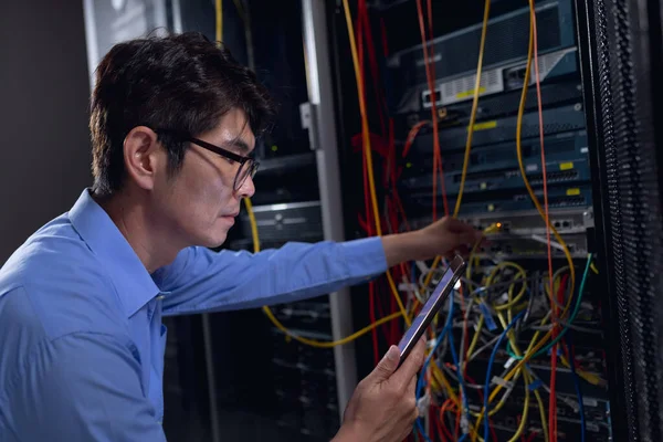 アジアの男性エンジニアは デジタルタブレットを使用してコンピュータサーバールームでコンピュータサーバーを検査します データベースサーバー管理とメンテナンスの概念 — ストック写真