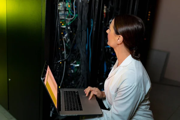 高加索女工程师穿着围裙 在计算机服务器室检查时使用笔记本电脑 数据库服务器管理和维护概念 — 图库照片