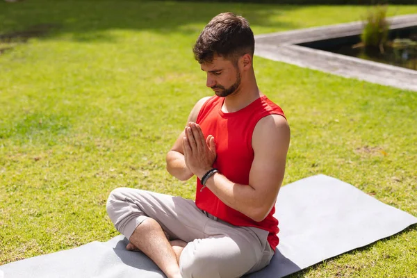Young Man Sitting Hands Clasped Cross Legged While Meditating Park — Stockfoto