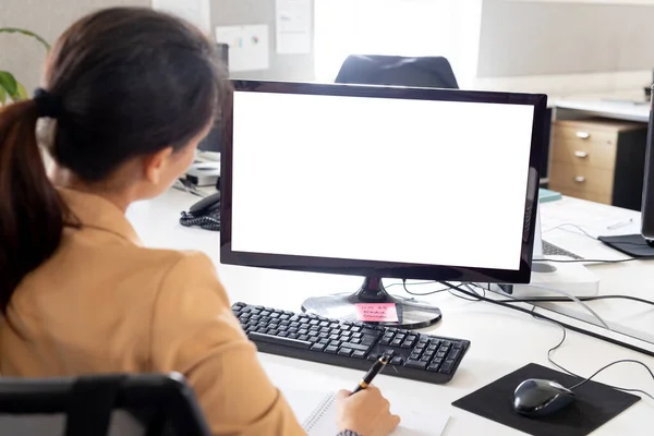 オフィスのデスクでコンピュータモニタ上で働く実業家の背面図 コピースペース 変化のない創造的なビジネス広告技術のコンセプト — ストック写真