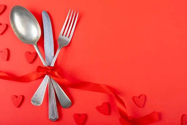 コピースペースと赤い背景の上にリボンで結ばれたカトラリーのオーバーヘッドビュー バレンタインデーと愛のコンセプト — ストック写真