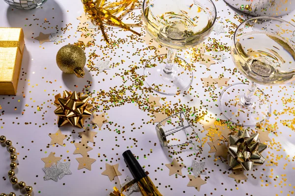 香槟酒杯的高角形景观散落在五花八门的五彩纸屑上 桌上有礼品和装饰 圣诞节庆祝活动和带有复制空间的聚会 — 图库照片