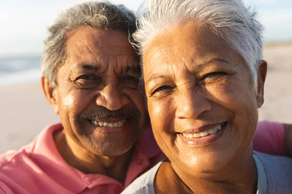 ビーチで夕日を楽しむ白い髪を持つ笑顔の多人種シニアカップルのクローズアップ肖像画 ライフスタイル愛週末 — ストック写真