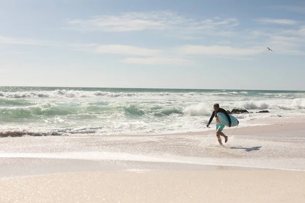 Emerytowany Dwurasowy Starszy Mężczyzna Biegający Deską Surfingową Brzegu Plaży Słoneczny — Zdjęcie stockowe