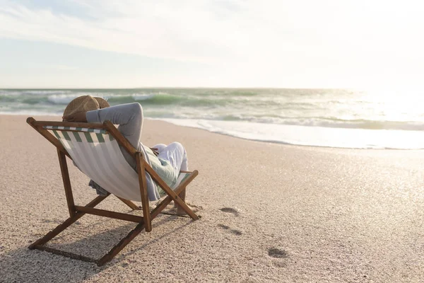 ビーチで夕日を楽しむ折り畳み式の椅子に座っているリラックスした引退した高齢の出産の女性 ライフスタイルと週末 — ストック写真