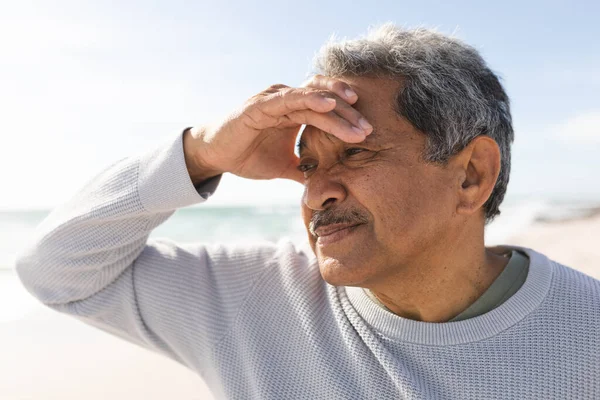 Emerytowany Dwurasowy Starszy Mężczyzna Odwraca Wzrok Osłaniając Oczy Dłonią Plaży — Zdjęcie stockowe