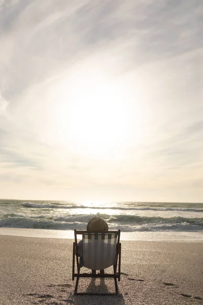 Senior Biracial Γυναίκα Κάθεται Πτυσσόμενη Καρέκλα Χαλαρώνοντας Στην Παραλία Μπροστά — Φωτογραφία Αρχείου