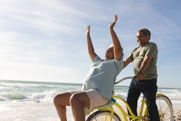 阳光明媚的日子里 当男人骑自行车在海滩上时 快乐的老女人在欢呼 积极的生活方式和交通 — 图库照片