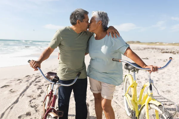 Στοργική Πολυφυλετικό Ηλικιωμένο Ζευγάρι Φιλιά Ενώ Στέκεται Κύκλους Ηλιόλουστη Παραλία — Φωτογραφία Αρχείου