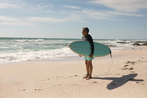 Pełna Długość Dwurasowego Starszego Mężczyzny Niosącego Deskę Surfingową Stojącego Plaży — Zdjęcie stockowe
