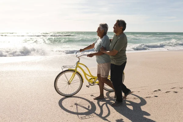 在阳光明媚的日子里 多种族的老年夫妇骑着自行车在海滨散步的侧视图 积极的生活方式和交通 — 图库照片