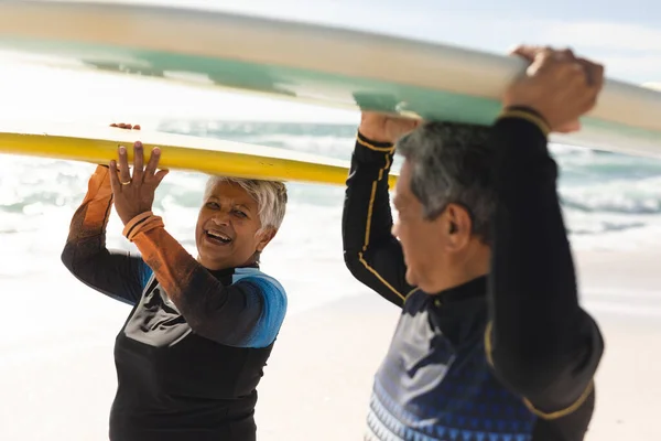 Radosna Starsza Dwurasowa Kobieta Niosąca Deskę Surfingową Nad Głową Patrząca — Zdjęcie stockowe