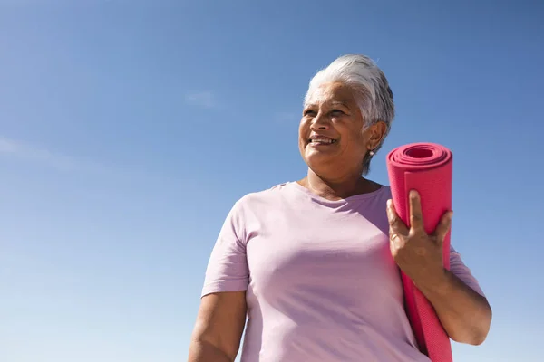 Leende Biracial Senior Kvinna Håller Rullade Upp Yogamatta Stranden Mot — Stockfoto