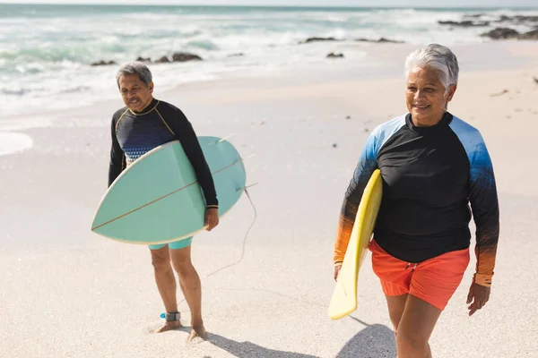 Dwurasowa Para Seniorów Deskami Surfingowymi Spacerująca Plaży Słoneczny Dzień Sporty — Zdjęcie stockowe