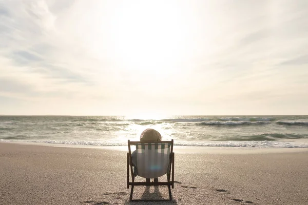 退休的老女人坐在折叠椅上 在海平线前的海滩上放松身心 生活方式和周末 — 图库照片