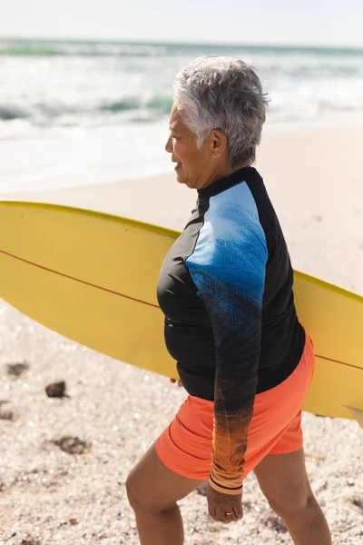Widok Boku Birasową Starszą Kobietę Kombinezonie Spacerującą Żółtą Deską Surfingową — Zdjęcie stockowe