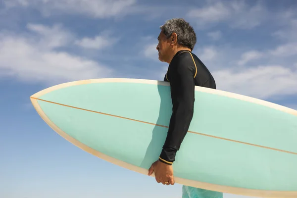 Zijaanzicht Van Biracial Senior Man Dragen Surfplank Het Strand Tegen — Stockfoto