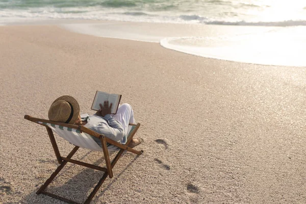 Расслабленная Старшая Расовая Женщина Читает Книгу Сидя Складном Стуле Пляже — стоковое фото