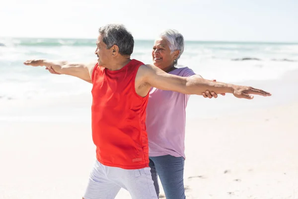 在阳光普照的海滩上 微笑着帮助男人伸展着双臂的老年女性 积极的生活方式和健身 — 图库照片