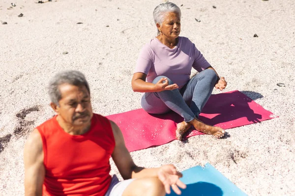 Biracial Senior Man Vrouw Mediteren Lotus Positie Trainingsmatten Zonnig Strand Stockafbeelding