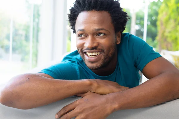 Gelukkige Afro Amerikaanse Jongeman Die Wegkijkt Terwijl Hij Thuis Bank — Stockfoto