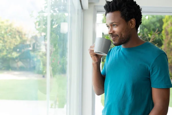 Afro Americano Sorridente Beber Café Enquanto Olhava Pela Janela Conceito — Fotografia de Stock