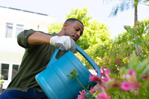 Młody Afroamerykanin Podlewanie Roślin Kwitnących Puszki Podczas Ogrodnictwa Podwórku Ludzie — Zdjęcie stockowe