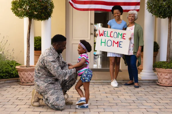 微笑着快乐的非洲裔美国女人拿着标语牌看着军人问候女儿 团结和爱国主义 — 图库照片