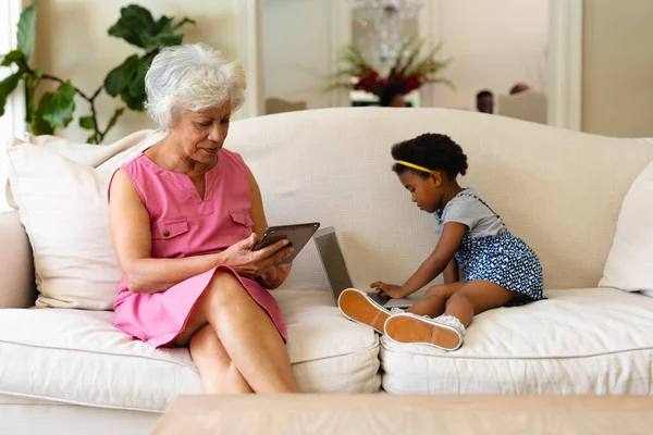 Африканська Бабуся Американка Використовує Цифровий Планшет Онуку Використовуючи Ноутбук Дивані — стокове фото