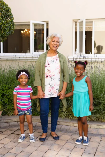 アフリカ系アメリカ人の祖母が孫娘の手を取り 屋外で笑っている姿を描いています 家族愛と団結の概念を変えずに — ストック写真