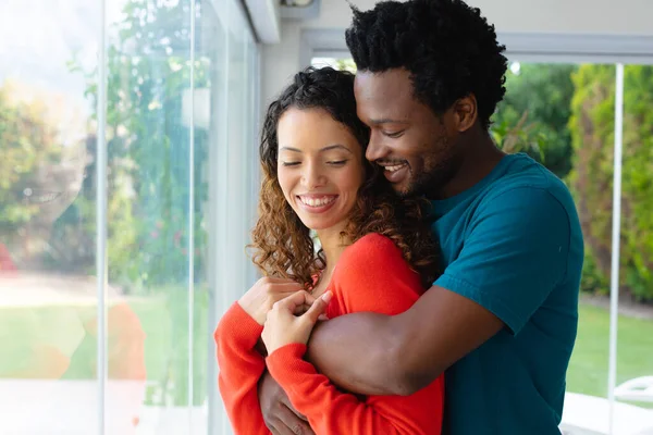 Feliz Casal Biracial Jovem Romântico Abraçando Enquanto Está Janela Casa — Fotografia de Stock