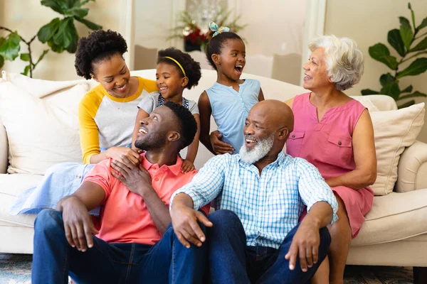 アフリカ系アメリカ人の3世代の家族が家でソファに座って見て笑っています 家族愛と団結の概念を変えずに — ストック写真