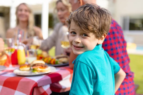 在花园里和家人一起坐在桌旁笑着的高加索男孩的后视镜画像 聚会和周末生活方式概念 — 图库照片