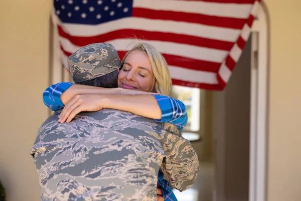 快乐的金发碧眼的高加索女人在士兵回家的门口拥抱他 爱和爱国主义的概念 — 图库照片