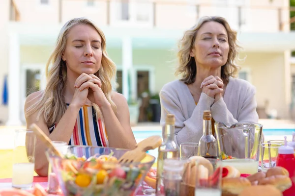 白人妇女和女儿紧闭双眼 双手紧握着双手 坐在花园里祈祷 团聚和灵性概念 — 图库照片