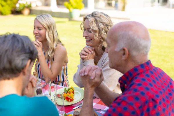 庭のテーブルで祈っている2世代の白人家族を笑顔 週末のライフスタイルの概念は — ストック写真