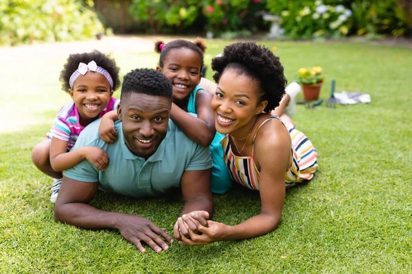 一个面带微笑的非洲裔美国人的画像躺在后院花园的草坪上 爱情和融合概念 — 图库照片