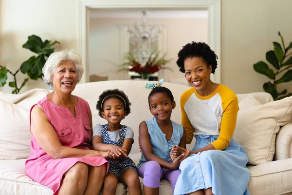 アフリカ系アメリカ人の祖母 母親と2人の孫娘の肖像画がソファに座って笑っている 家族愛と団結の概念を変えずに — ストック写真