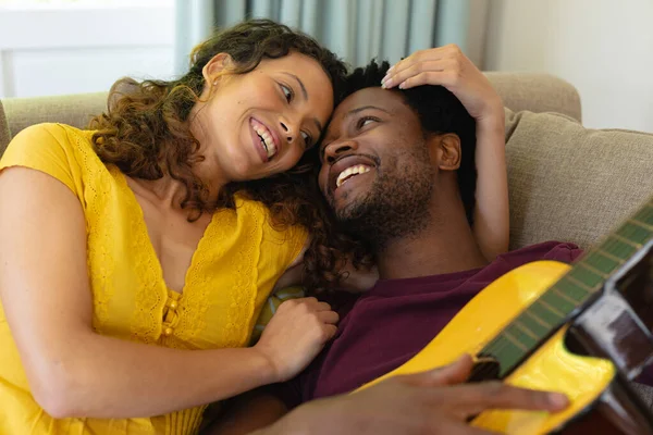 Sorrindo Jovem Casal Multirracial Romancear Enquanto Deitado Com Guitarra Casa — Fotografia de Stock